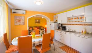 奥瑞比克Apartment Želja - big terrace的厨房配有橙色和白色的橱柜和桌子