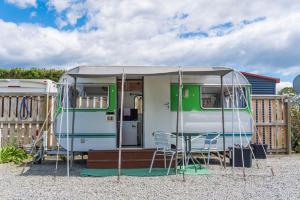 LeithfieldLeithfield Beach Holiday Park的绿色和白色的大篷车,配有桌椅