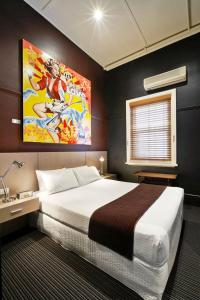 墨尔本托拉诺酒店的卧室配有一张大床,墙上挂有绘画作品
