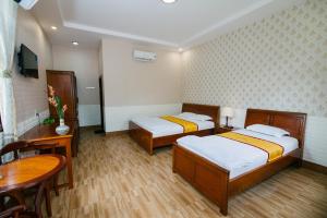 芹苴Mỹ Khánh Resort的一间卧室配有两张床、一张桌子和一张桌子