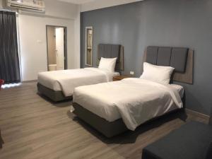 坤敬Neo Hotel的酒店客房,配有两张带白色床单的床