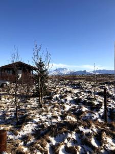海拉Fögruvallakot Cabin的雪覆盖的田野,有房子的背景
