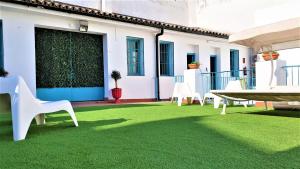 塞维利亚Casual de las Letras Sevilla的庭院设有白色椅子和绿色草坪。