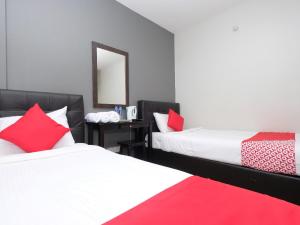 关丹Elite Hotel的一间卧室配有两张带红色枕头和镜子的床
