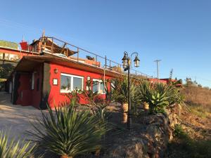 蒂哈拉费HRlos Piratas - Ferien Haus La Palma - GOOD WLAN !!的前面有植物的红色房子