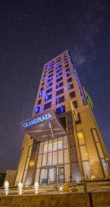 利雅德Grand Plaza Hotel - KAFD Riyadh的一座高大的建筑,晚上有标志