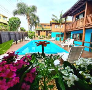 瓜尔达恩巴Pousada Doce Mar的后院,带游泳池和一些鲜花
