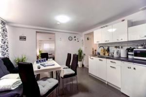 莱斯科Apartamenty Bieszczady的厨房配有白色橱柜和桌椅