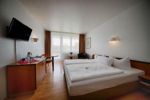 柏林附近贝尔瑙贝尔瑙舒适酒店的酒店客房设有一张白色大床和一张桌子。