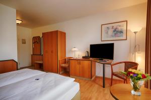 柏林附近贝尔瑙贝尔瑙舒适酒店的一间卧室配有一张床和一张书桌及电视