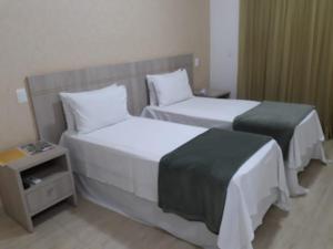 里贝朗普雷托香格里拉旅馆的酒店客房设有两张床和床头柜。