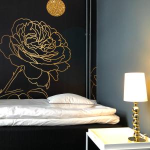 布罗斯Mini-Hotel Borås Regementet的卧室的墙上挂着一朵黑色和金色花