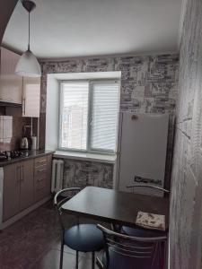 切尔尼戈夫Apartment with balcony on Peremohy Avenue 43的厨房配有桌椅和冰箱。