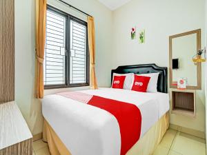 加拉旺OYO Life 90211 I-sidji Inn的一间卧室配有一张带红色枕头的大床