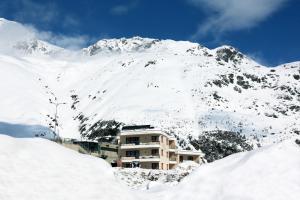 索尔登Apartmenthaus Enzian Hochsölden的雪覆盖的山前的建筑物