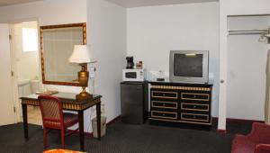 章克申城Golden Wheat Budget Host Inn Junction City的酒店客房设有电视和带桌子的书桌。