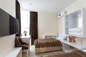 费尔干纳Tantana Hotel的配有一张床和一把椅子的酒店客房