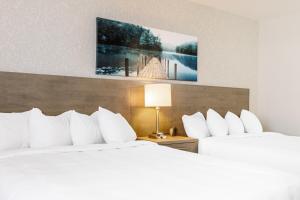 魁北克市Repotel Henri IV Québec的配有白色枕头的酒店客房内的两张床