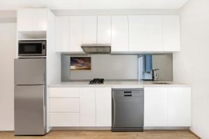悉尼Bondi Beach Studios Suite的厨房配有白色橱柜和不锈钢冰箱
