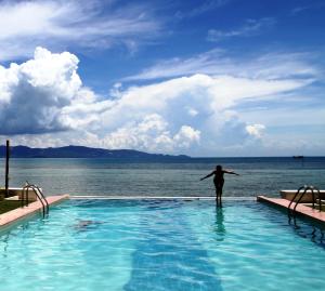 班泰神曲海滩度假酒店的站在水边的游泳池里的人
