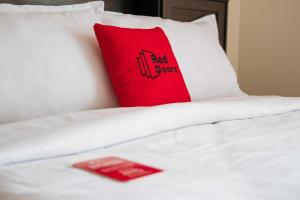 SinapuranRedDoorz Plus @ Vantas Hotel Parbaba的白色床顶上的红色枕头