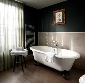 阿宾登王冠与蓟酒店的一间带白色浴缸和凳子的浴室