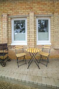 珀尔沃卡Vėjūnė的庭院配有两把椅子和一张桌子,并设有两扇窗户。