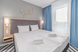 米兹多洛杰Sunny Apartments in Bel Mare Resort by Renters的卧室配有一张带蓝色窗帘的大型白色床