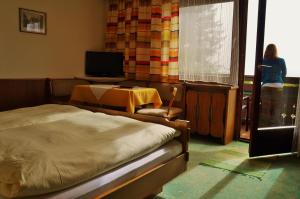 巴德加斯坦兰德豪斯赫勒斯黑慕赫尔酒店的一间卧室配有一张床、一张桌子和一台电视