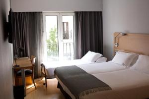 宏达瑞比亚Hotel Jauregui的酒店客房设有两张床和窗户。