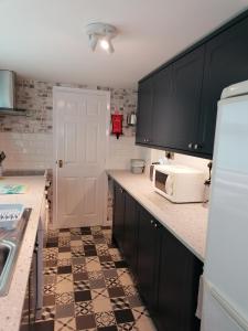 洛斯托夫特日出度假屋的厨房配有黑色橱柜和白色微波炉