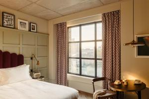 伦敦The Hoxton, Southwark的一间卧室设有一张床、一个窗口和一张桌子