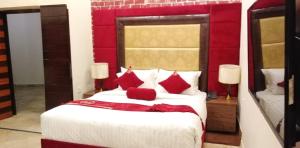 拉合尔Hotel The Holiday的卧室配有带红色枕头的大型白色床