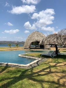 普拉纳维瑙Azuero Lodge: Luxury Beachfront condo- Playa Venao的一个带游泳池和草伞的度假胜地