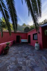 巴列埃尔莫索Casa Rural Abuelo Ramón的红色的房子,设有石头庭院和长凳