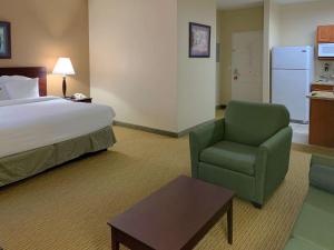 艾迪生MainStay Suites Addison - Dallas的配有一张床和一把椅子的酒店客房