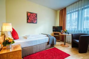 巴登-巴登比肖夫酒店的酒店客房配有床、沙发和电视。