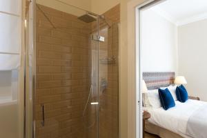 坎波巴索GMarconi Suites的卧室里设有淋浴,卧室里设有一张床和一个玻璃门