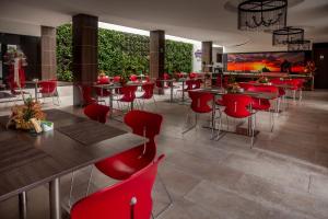波帕扬Hotel San Martin Popayan的餐厅设有红色的桌椅和大屏幕