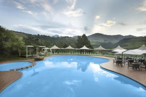 温特顿Drakensberg Sun Resort的一个带桌子和遮阳伞的大型游泳池