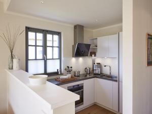 德兰斯克Reetland am Meer - Premium Reetdachvilla mit 3 Schlafzimmern, Sauna und Kamin E16的厨房配有白色橱柜和窗户。