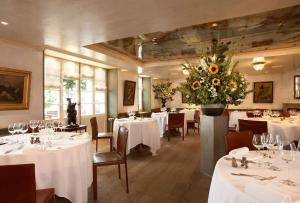 苏西Romantik Hotel de L'Ours的一间设有白色桌子和大花瓶的用餐室