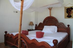 南威HOMELAND SWAHILI LODGE Nungwi Backpacker Apartments BUDGET的一张带白色床单和红色枕头的木床