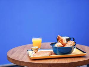 佩皮尼昂ibis Styles Perpignan Centre Gare的盘子上放着一碗面包和一杯橙汁
