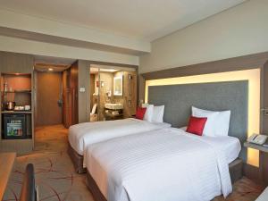 加尔各答加尔各答诺富特酒店及公寓的大型酒店客房,配有两张带红色枕头的床