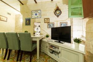 瓦莱塔Sant'Elmo House Valletta的客房设有一张桌子、一台电视和椅子