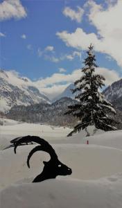 马洛亚Maloja Kulm Hotel的山羊在雪中在树旁的雕像