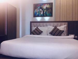 斋浦尔Hotel The Omaira的卧室配有一张白色大床,墙上挂有绘画作品