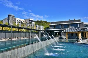 Yuanli享沐时光庄园渡假酒店的一座建筑中间的游泳池,有一个喷泉