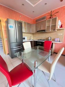 Petropavlovskaya BorshchagovkaТаунхаус 99的厨房配有玻璃桌和红色椅子